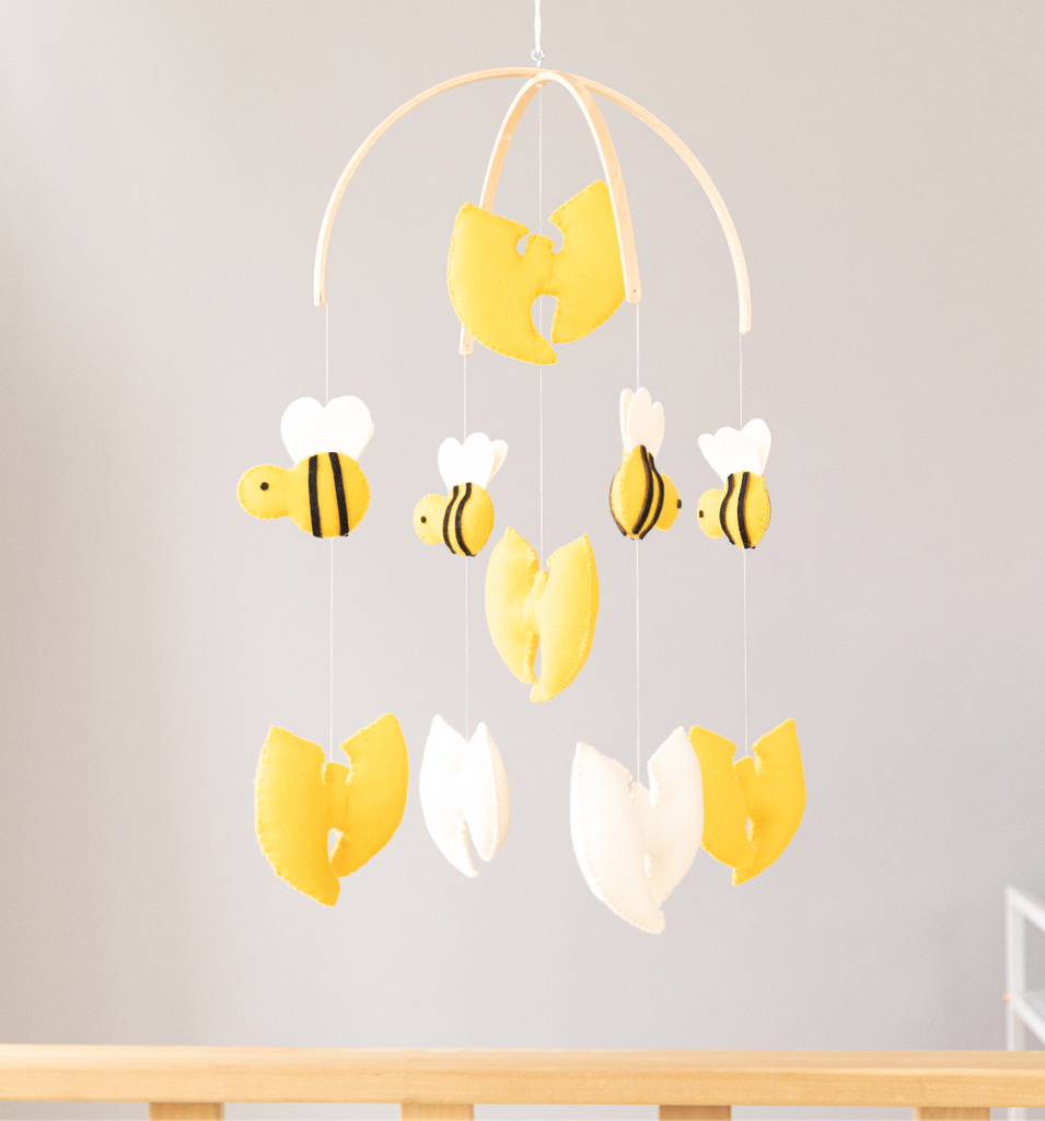 Crib mobile with puffy, yellow and white, felt Wu Tang-style W's and bumble bees hanging from a curved wood  frame