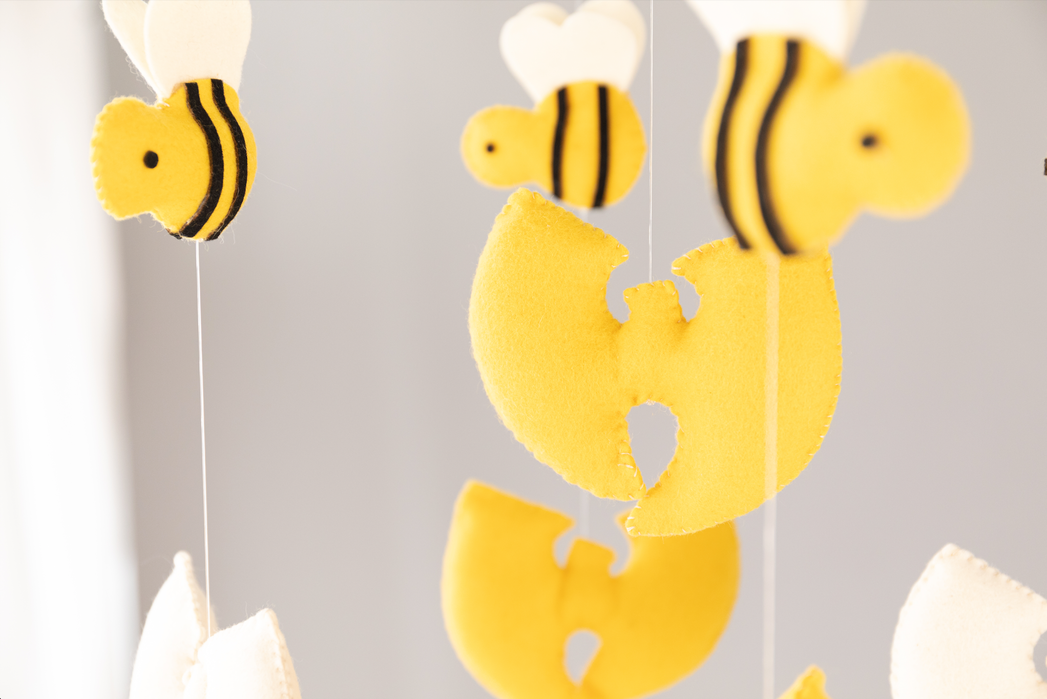 Yellow and white, puffy, felt Wu Tang-style W's and bumble bees hanging in the air